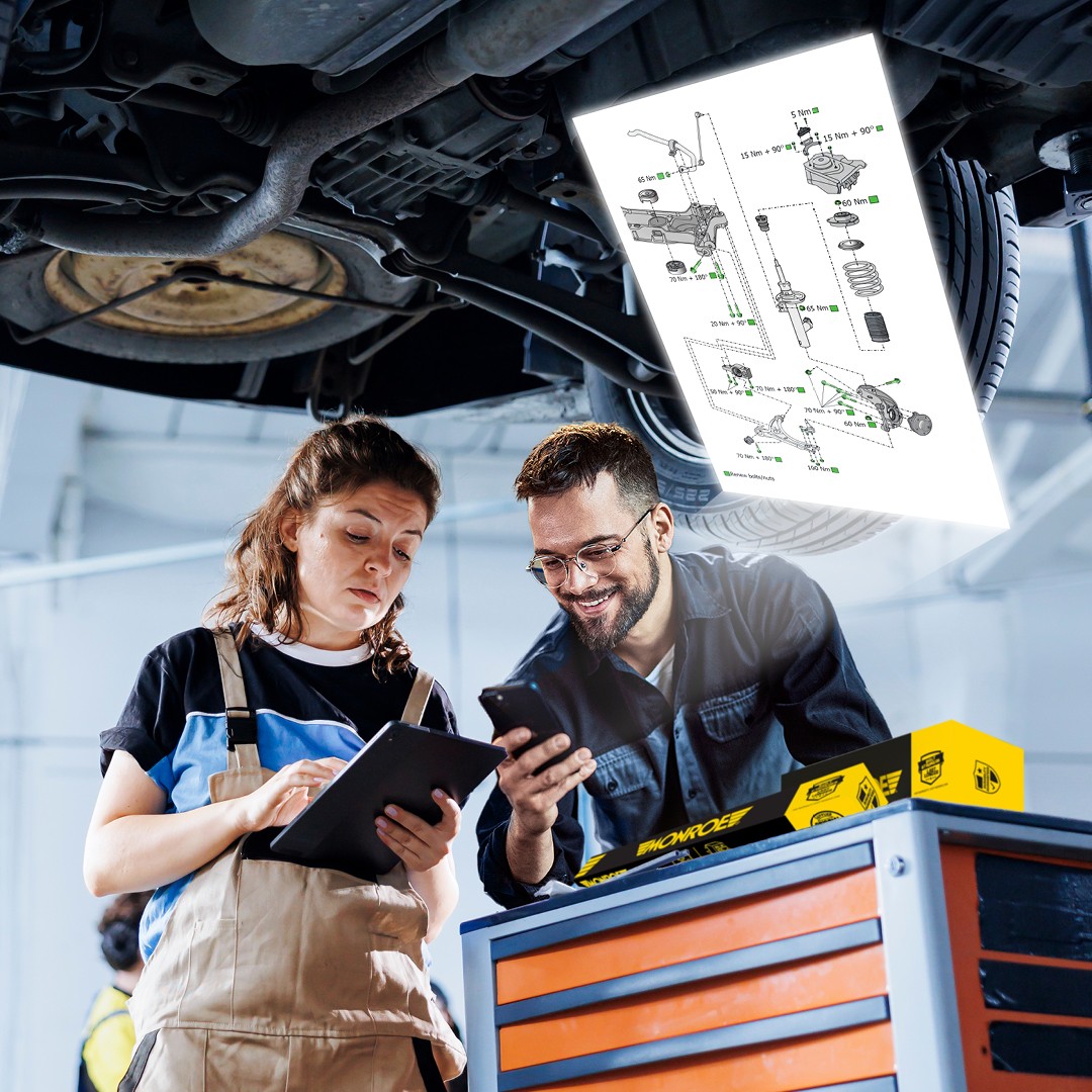 Two installers looking at the Monroe suspension technical drawing in a garage