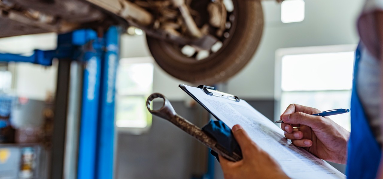 Technician with clipboard inspecting vehicle.