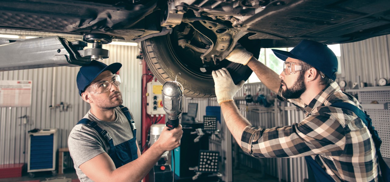 Technicians examining underbody of vehicle